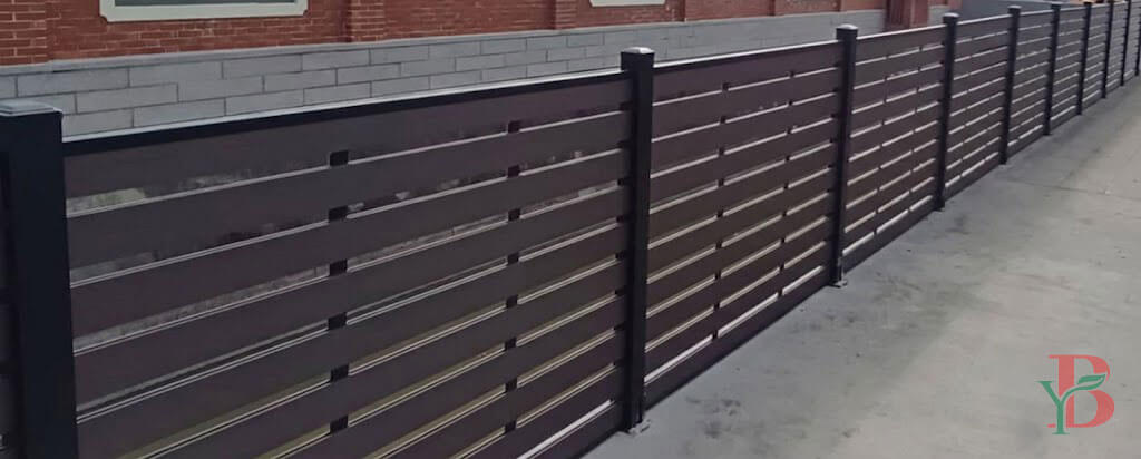 Modern dark brown WPC composite fence with horizontal slats and black aluminum posts for garden privacy