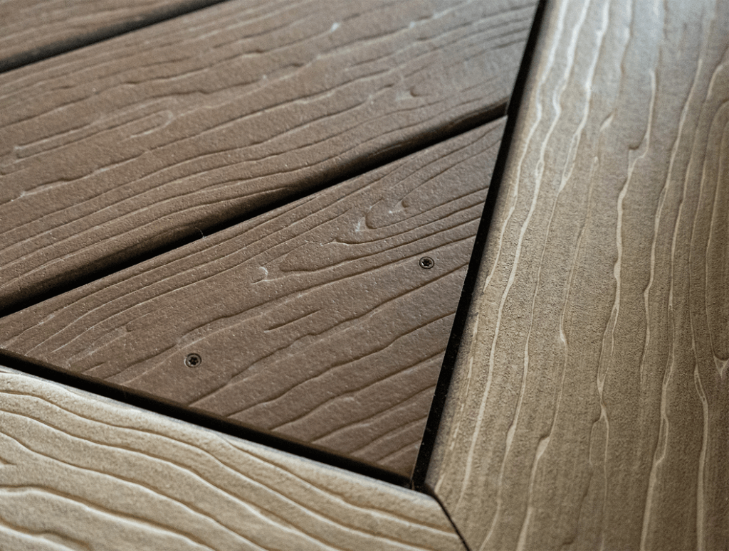 installing-metal-surface-fastener-pin-composite-decking Hand installing a metal surface fastener pin into brown composite decking