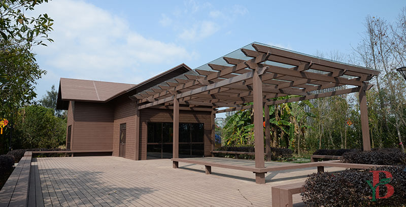 Attached WPC pergola connected to a building with a glass roof for space-saving outdoor living.