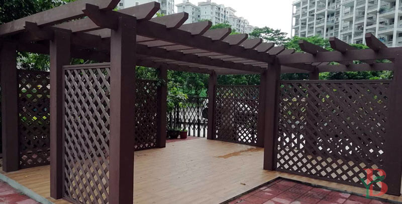Freestanding WPC pergola featuring decorative lattice privacy screens for flexible placement.