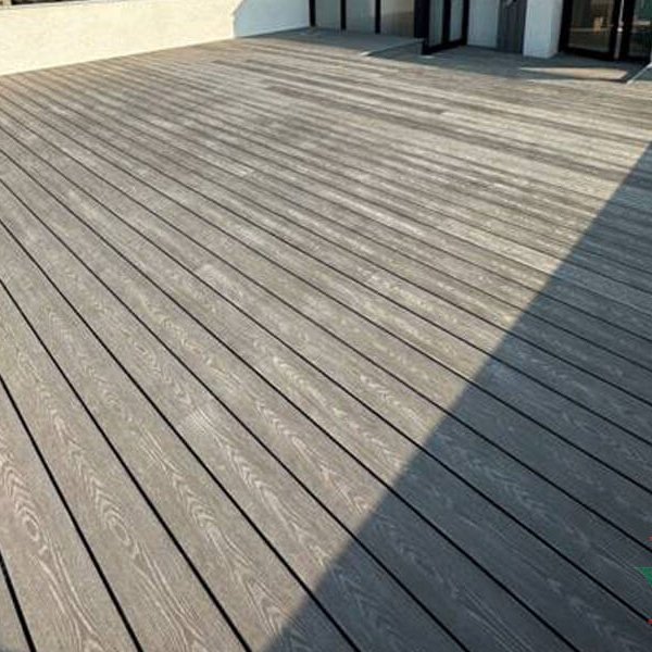 Wide view of a large rooftop terrace decked in modern gray wood plastic composite (WPC) decking