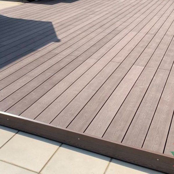 Rich brown composite decking patio with built-in steps and a vertical composite privacy wall.