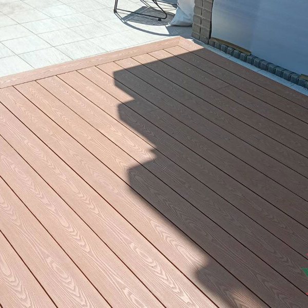 Dark brown composite decking platform on a tiled city balcony, used as a clean outdoor lounge space.