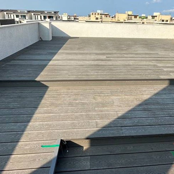 Multi-level gray composite deck installed on a sunny residential rooftop, creating raised seating areas