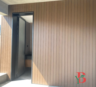 Professional installation of vertical WPC wall panels near a building entrance.