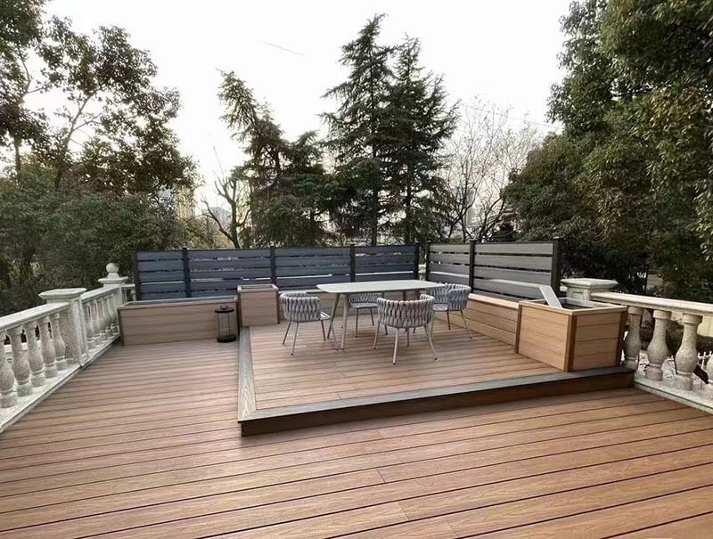 A wide residential patio featuring light brown capped composite decking with a modern dining set